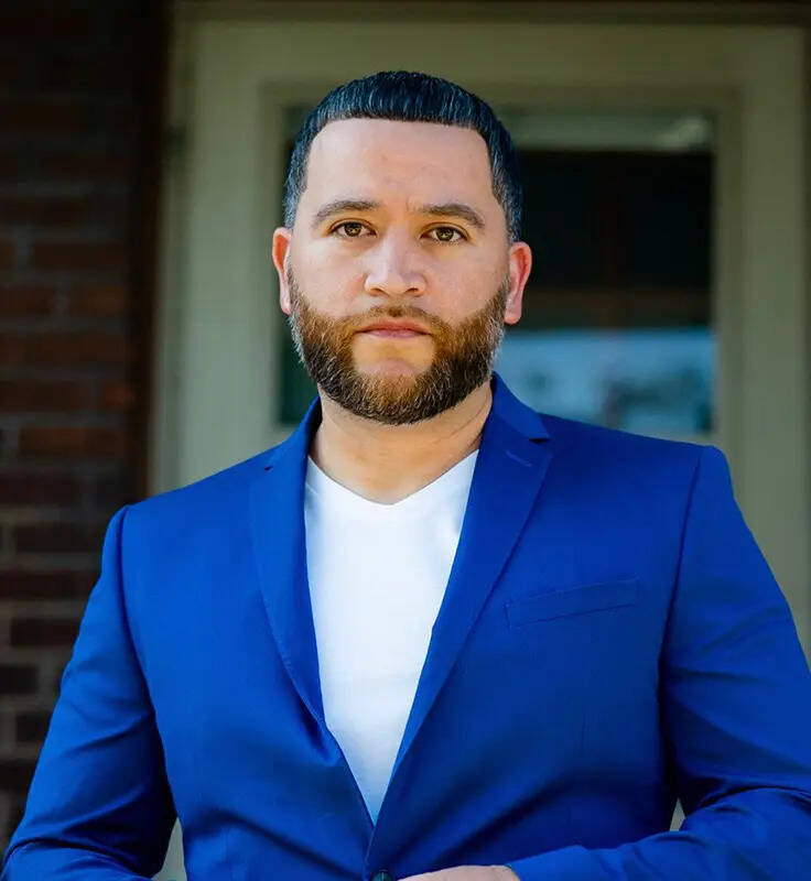 Dre Rodriguez standing in a blue suit